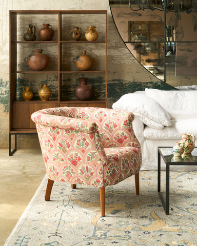 Decorative living room with floral armchair, wooden shelf with pots, and large mirror. Photographed in Eloise Fresa.