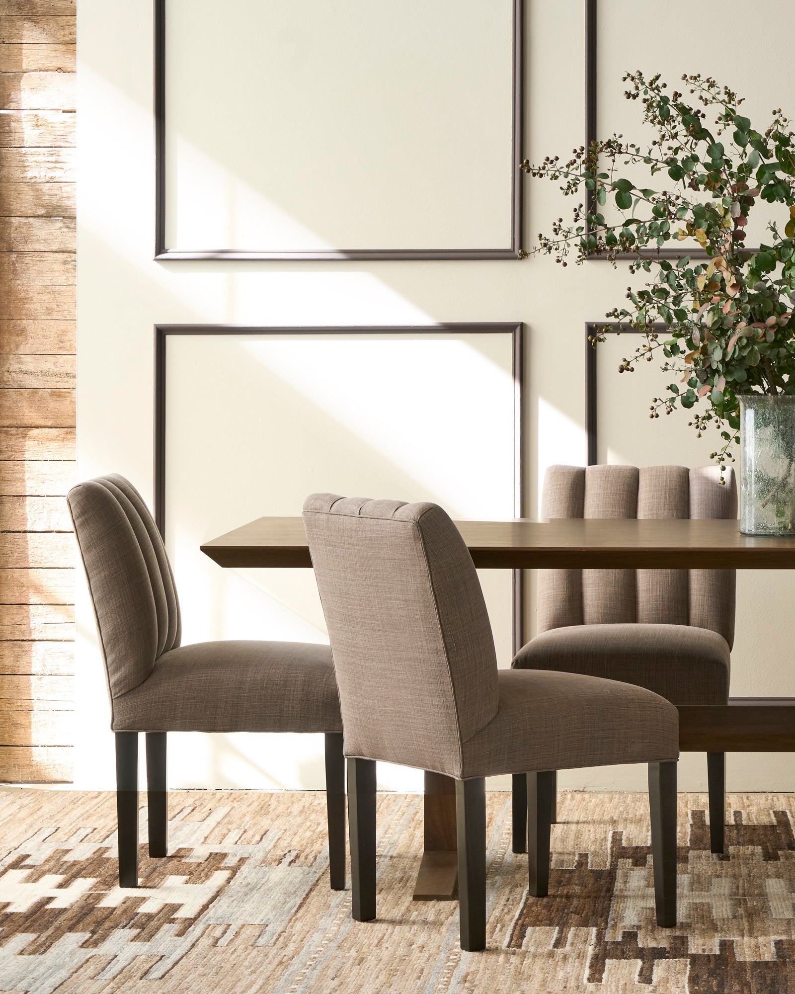  Dining room with a wooden table and upholstered chairs, featuring a neutral color palette. Photographed in JD Rye Acorn. 