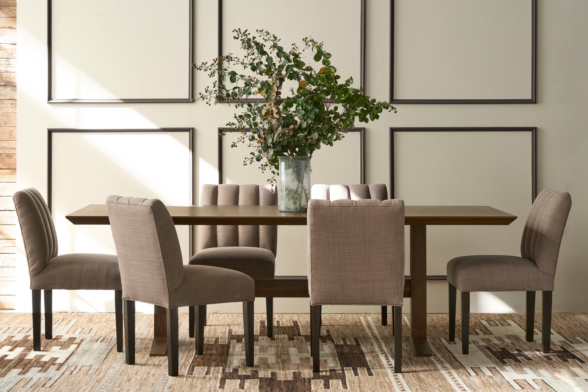  Dining room with a wooden table and gray chairs, featuring a vase with greenery. Photographed in JD Rye Acorn. 