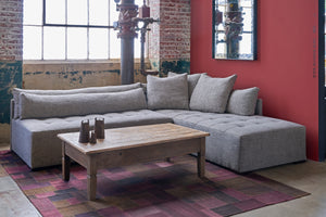  Sectional in grey in front of a window with a red wall on the right. Wood coffee table and patchwork rug. Photographed in Raven Peppercorn.  