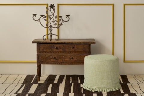 Wooden dresser with a candelabra and green ottoman on a patterned rug. Photographed in Sommerset Apple Green.
