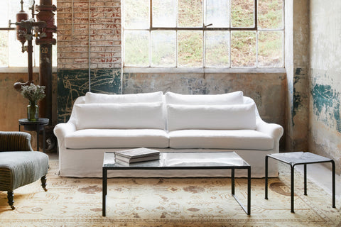 White slipcovered sofa in a showroom with a table in front. Photographed in Brevard Ivory.
