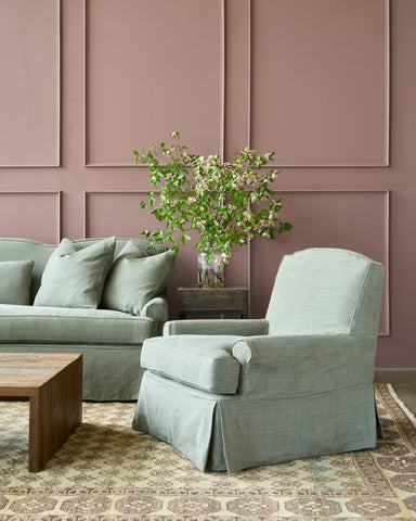 Living room with a gray sofa, armchair, and wooden coffee table against a paneled wall. Photographed in JD Rye Forest.