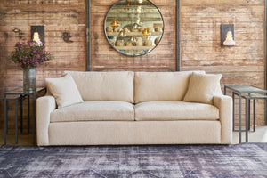  Sofa in a textured fabric in front of a wood wall with a round mirror. Photographed in Knobby Natural. 