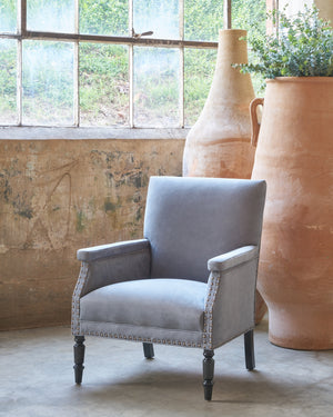  Chair in a showroom in front off tall terracotta pots and a  