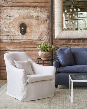  White slipcovered chair on the left of a blue sofa. Photographed in Brevard Ivory. 