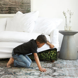  Boy lifting the edge of a sofa to reveal plants inside the sofa 