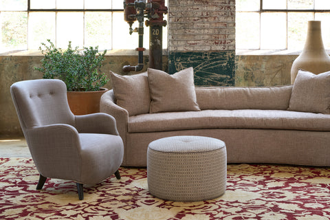 Sofa in a showroom with a chair and an ottoman. Photographed in Canasta Bark.