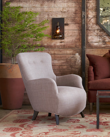 Gray armchair in a room with wooden walls, a red sofa, and a decorative plant. Photographed in JD Rye Acorn.