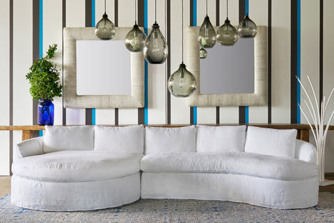 White sectional sofa in a room with striped walls and hanging light fixtures. Photographed in Logan White.