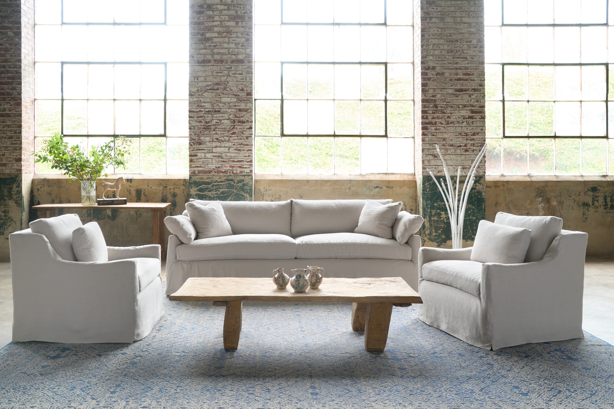  Sofa and 2 chairs in a showroom with a wood coffee table and a white floor lamp. Photographed in Brevard Mist. 