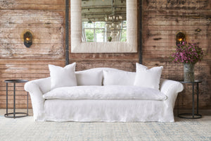  White slipcovered sofa in front of a wood wall. Photographed in Brevard Ivory. 