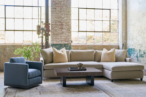  Sectional sofa in front of large windows with a striped blue chair on the left. Wood coffee table in the middle. Photographed in Beach Spice. 