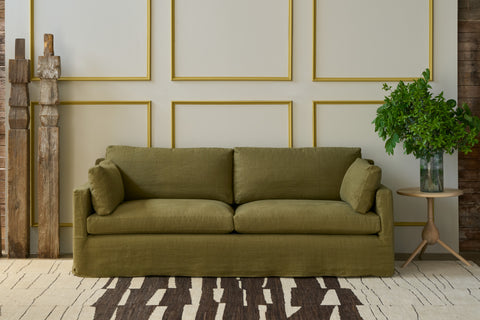 Green sofa in a room with decorative wall panels and a plant. Photographed in Devon Army.