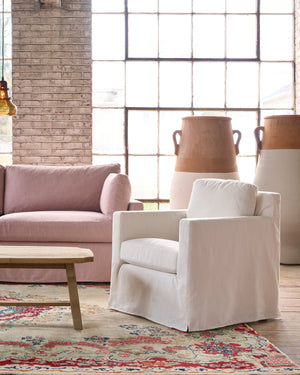  White slipcovered chair next to a ink sofa. Photographed in Elder Ivory. 