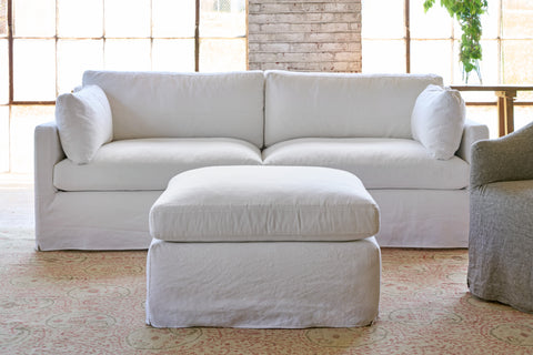 White ottoman in front of a white sofa. Photographed in Miles White.