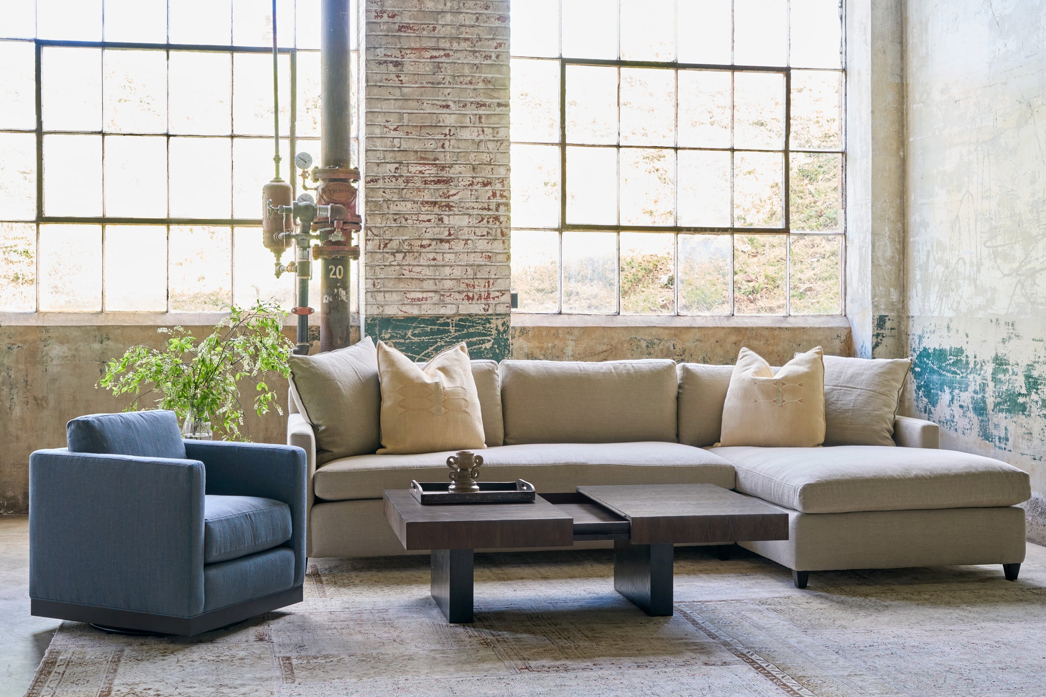  Sectional sofa in an oatmeal color with a Cosmo Mini Chair on the left side. A coffee table in wood that expands is in front. Photographed in Ashville Burlap. 