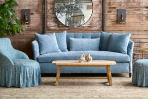  Blue sofa with matching armchairs in a rustic living room setting. 