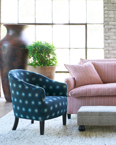 Blue chair with flowers next ro a striped sofa and an ottoman. Photographed in Daisy Blue.
