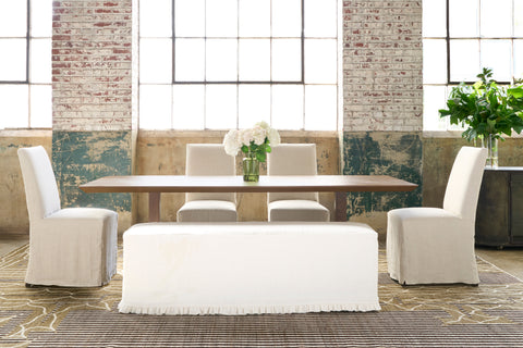Dining table in a showroom with 4 chairs all slipcovered in white linen. Photographed in Brevard Ivory.