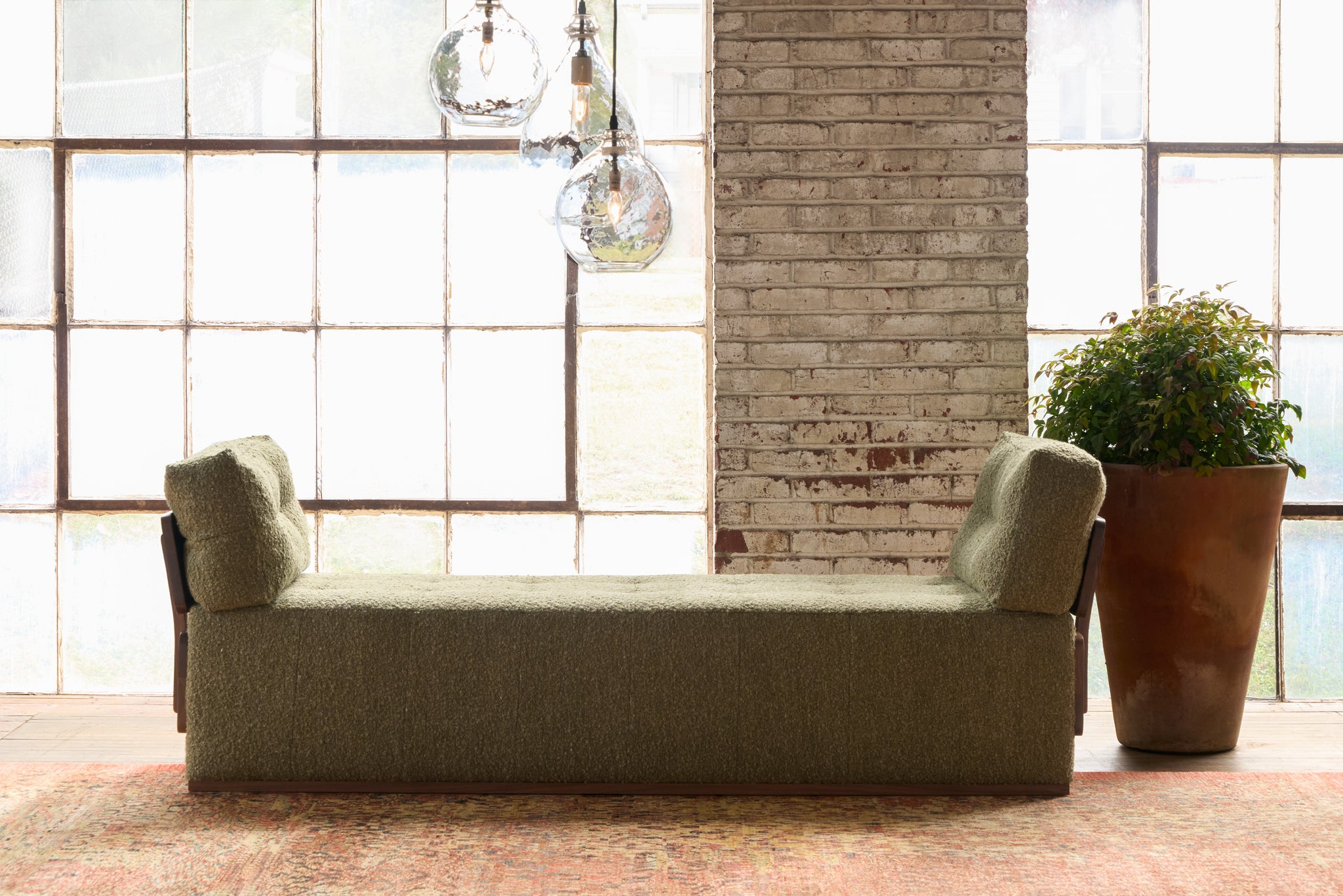  Green daybed in front of a window with a plant. Photographed in Knobby Moss. 