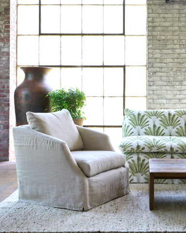 Beige armchair in a room with a patterned sofa and large vase. Photographed in Ashville Oatmeal.