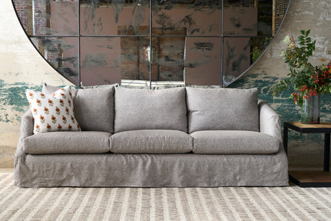 Gray sofa in a room with decorative wall mirrors and a small table with flowers. Photographed in Sommerset Smoke.