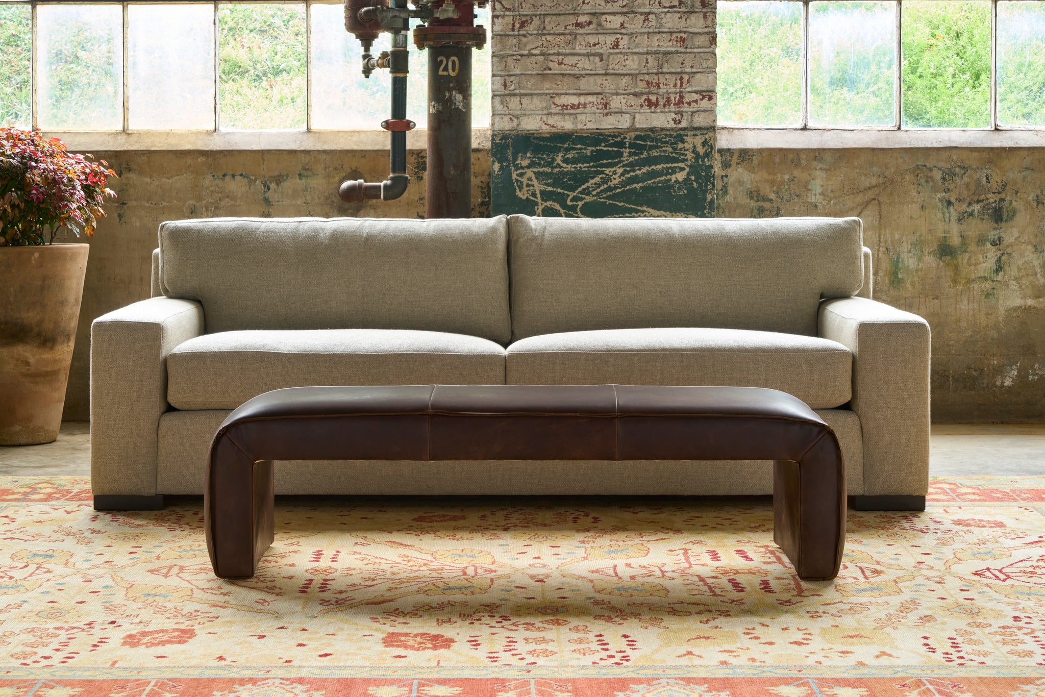  Leather bench in front of a sofa with 2 seat cushions and 2 back pillows. Photographed in Spur Chocolate. 