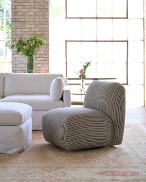  Striped chair next to a white sofa. Large window in the background and flowers on a side table. Photographed in Hickory Noire. 