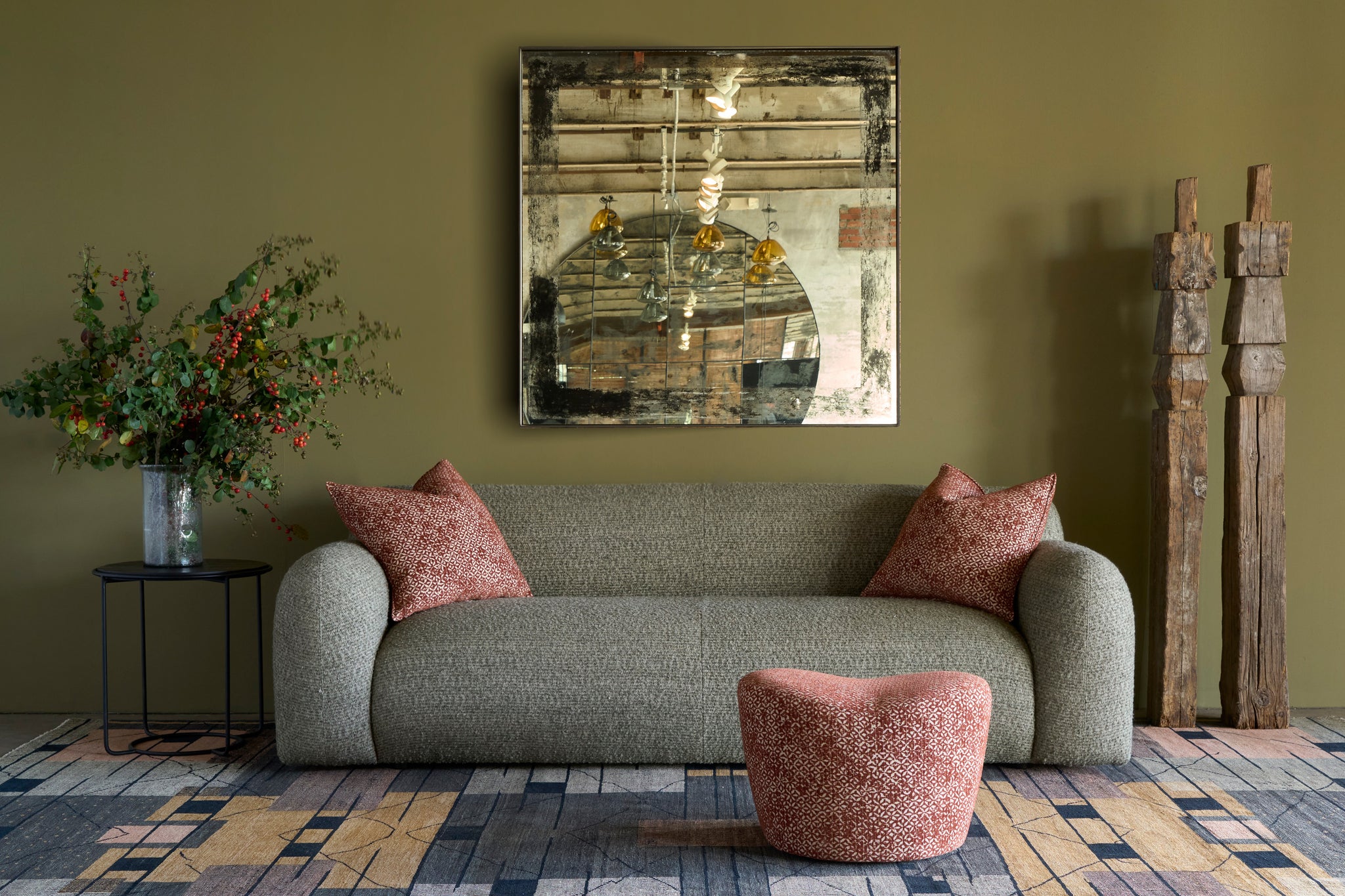  Living room with a green sofa, pink cushions, and a decorative painting on a green wall. Photographed in Caspian Sage. 
