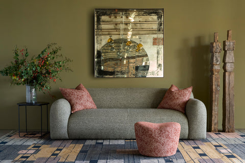 Living room with a green sofa, pink cushions, and a decorative painting on a green wall. Photographed in Caspian Sage.