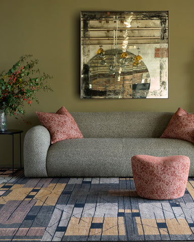 Gray sofa with pink cushions in a living room setting with a large mirror on the wall.