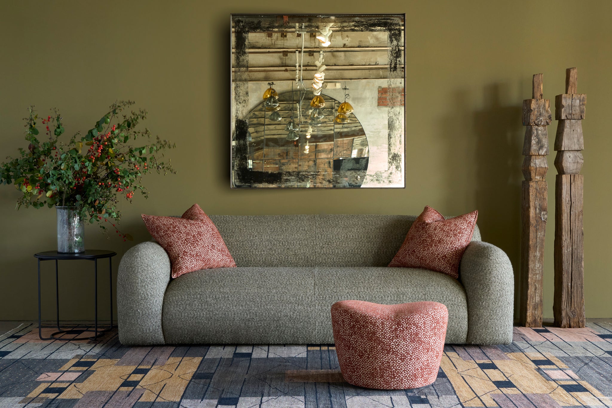  Living room with a gray sofa, red cushions, and a decorative painting on a green wall. Photographed in Caspian Sage. 