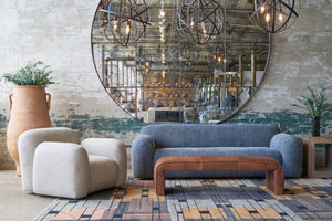  Chair in a showroom in front of an oversized mirror with a grey sofa on the right. Photographed in Bellamy Oatmeal. 