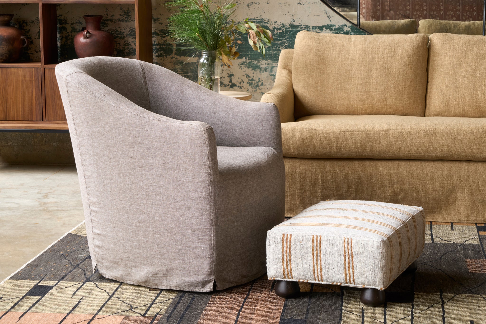  Gray armchair with a matching ottoman in a living room setting. Photographed in Vintage Hemp. 