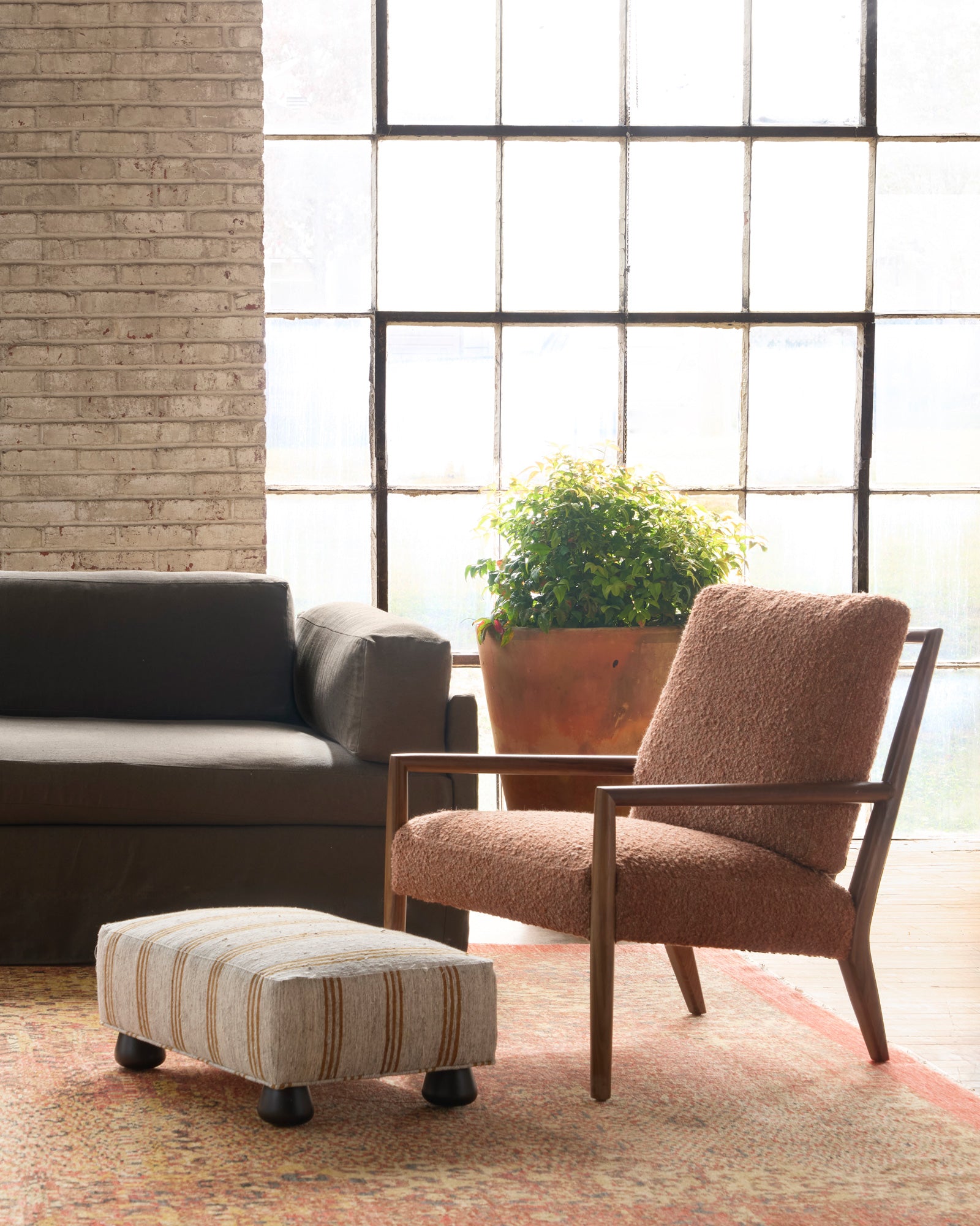  Living room with a brown armchair, gray sofa, and patterned ottoman. Photographed in Vintage Hemp. 