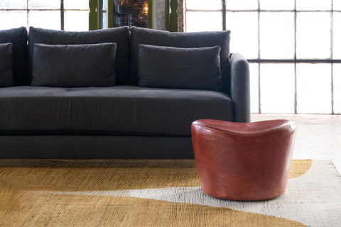 Black sofa with a leather ottoman on a yellow and white rug. Photographed in Solvang Chianti.