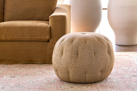 Yellow pouf ottoman in front of a dark yellow sofa. Photographed in Ferrara Maize.