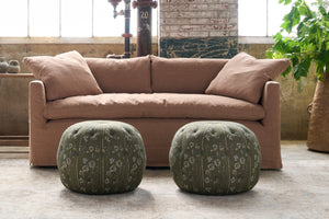  Two green poufs with a floral motif in front of a brown sofa. Photographed in Foret Fir. 