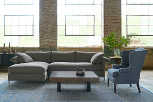  Sectional sofa in dark grey linen with a wing chair on the right and a wood coffee table. Photographed in Beach Spice. 