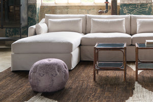  Sectional sofa in cream fabric with 2 small tables in front and a pouf on the brown rug. Photographed in Emre Persian Pink. 