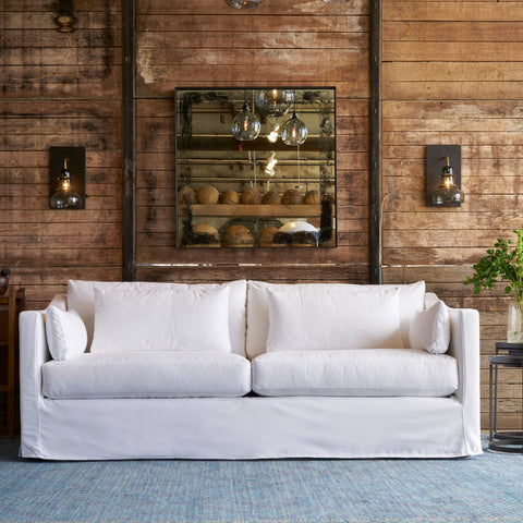 White sofa in a room with wooden walls and decorative elements. Photographed in Denim White.