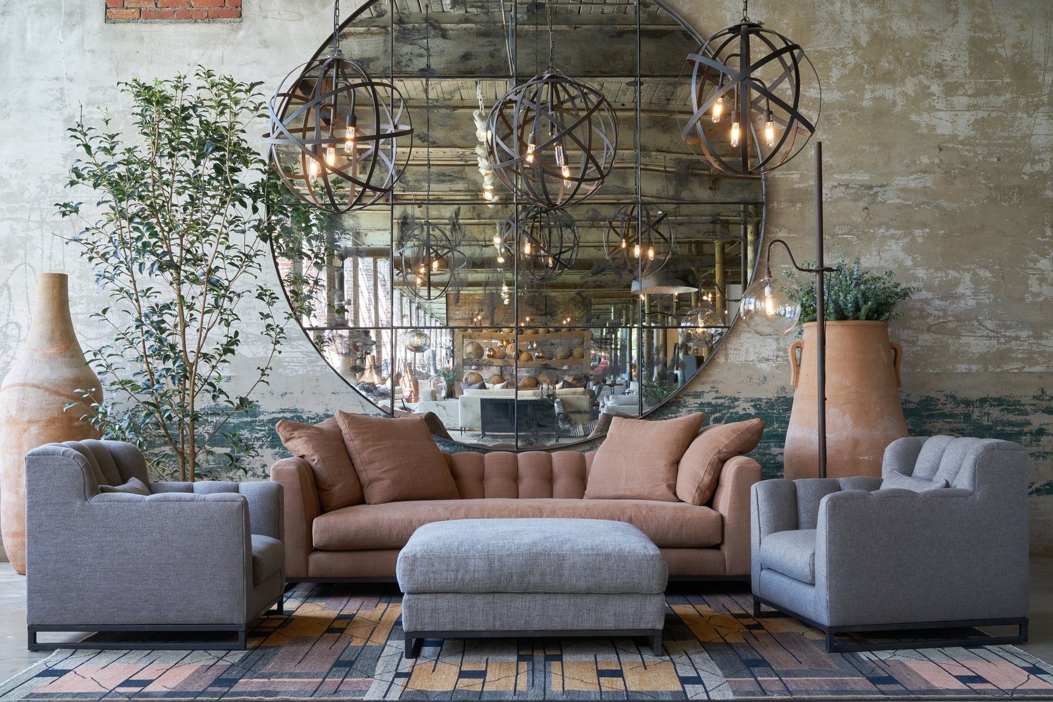  Sofa and armchair setting in a showroom in front of a large mirror with a tree on the left. Photographed in Rye Spice. 
