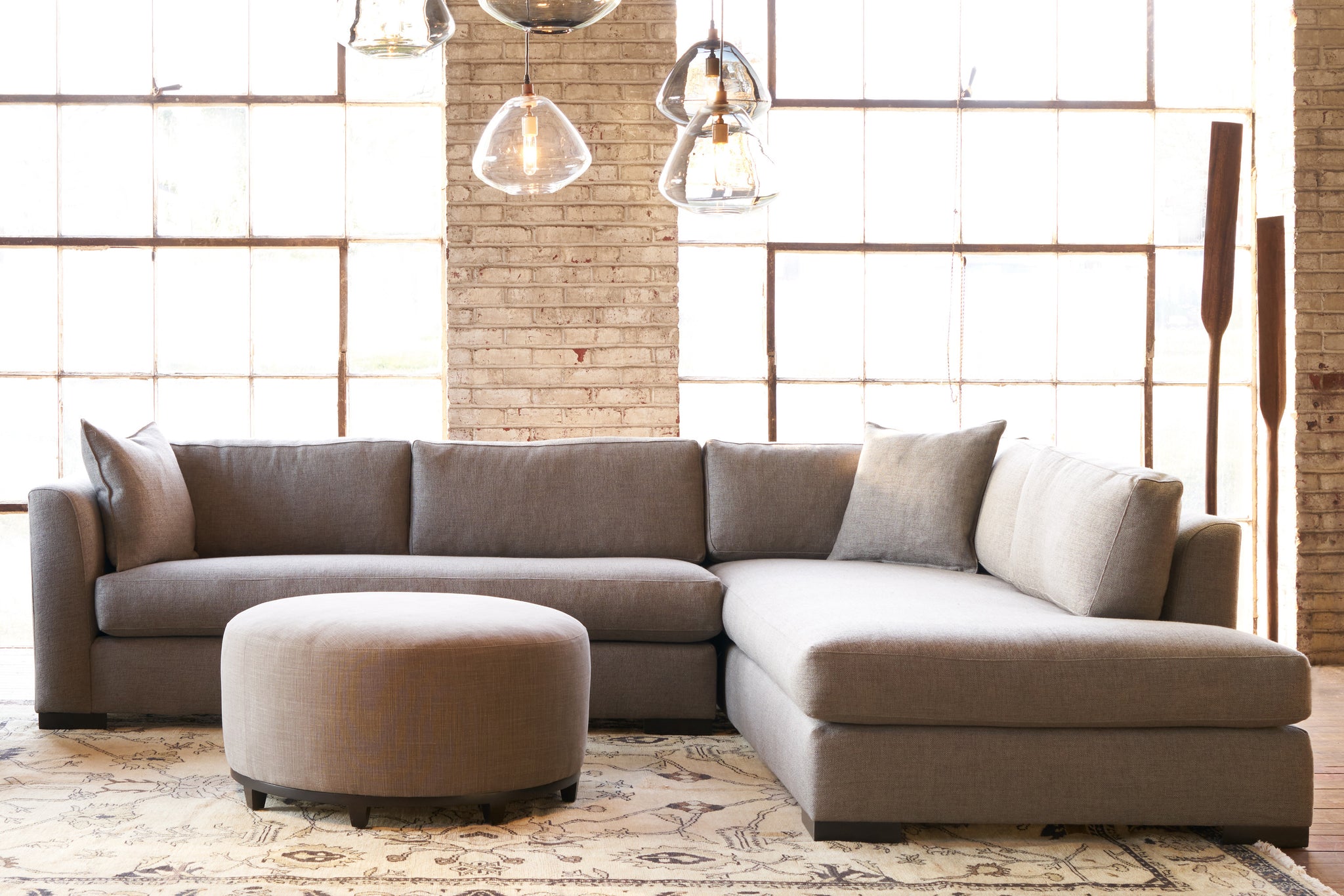  Sectional in front of windows with a round ottoman in front. Photographed in Bellamy Pewter. 