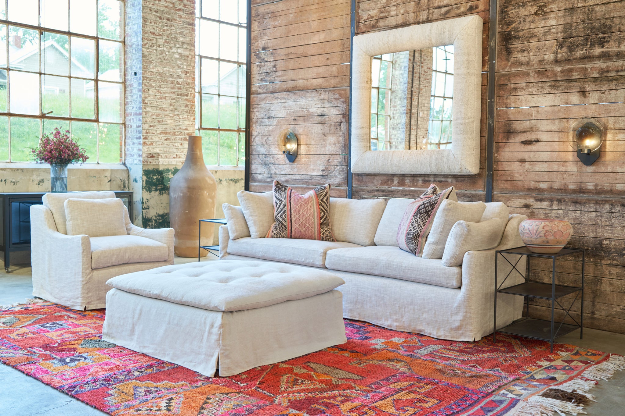  Sofa in a showroom with a chair on the left and a tufted ottoman in the center. Photographed in Brevard Birch. 