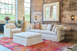  Showroom setting with an oatmeal sofa with a chair on the left and a square tufted ottoman in the center. Photographed in Elijah Tan. 