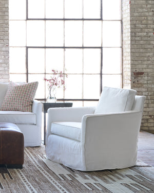  White chair on a brown  rug in front of a leather ottoman.  Photographed in Ashville. 