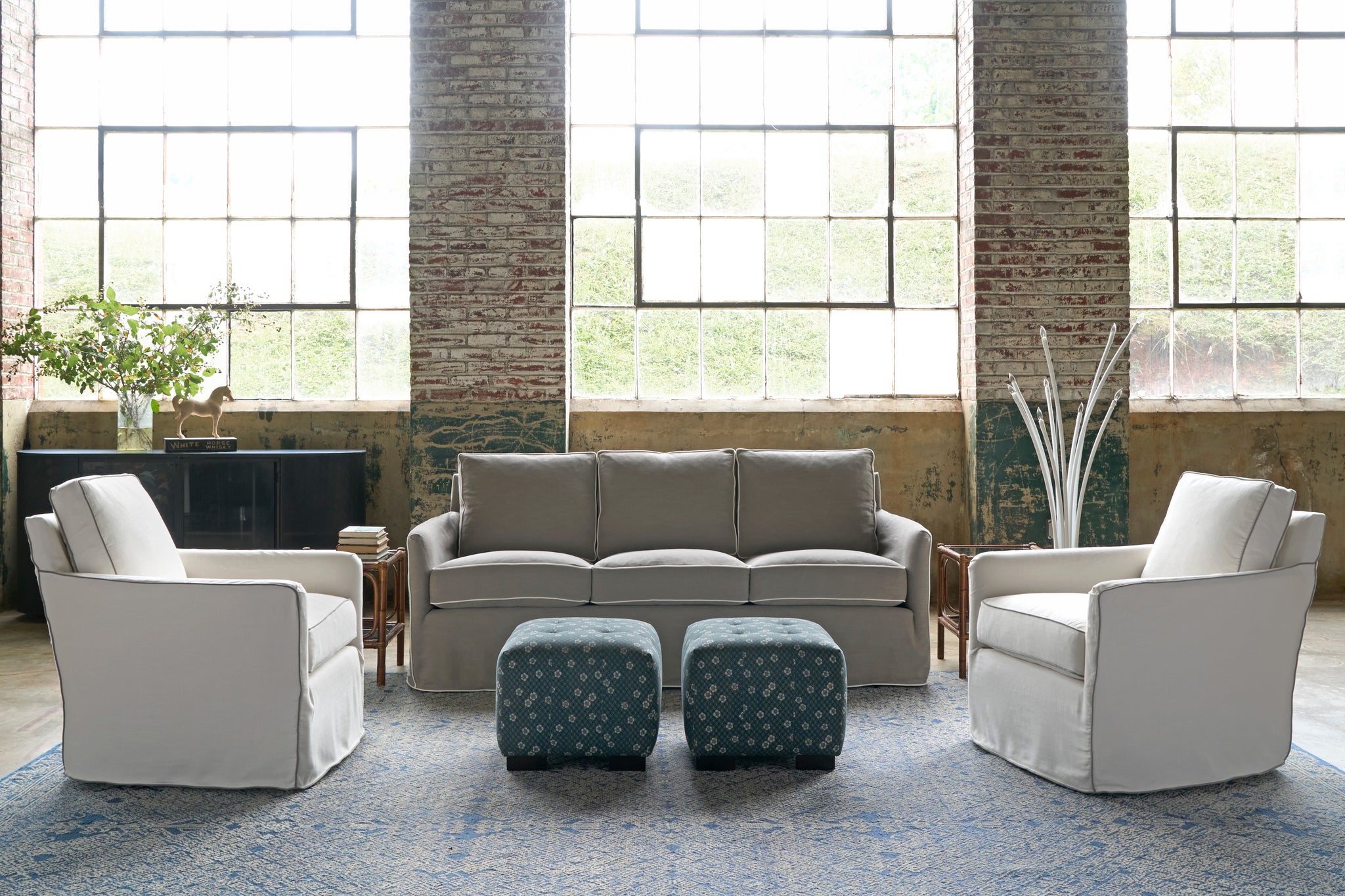  Showroom with a grey sofa, 2 white chairs and 2 ottomans with floral blue fabric. Blue and white rug. Photographed in Molino Fog. 