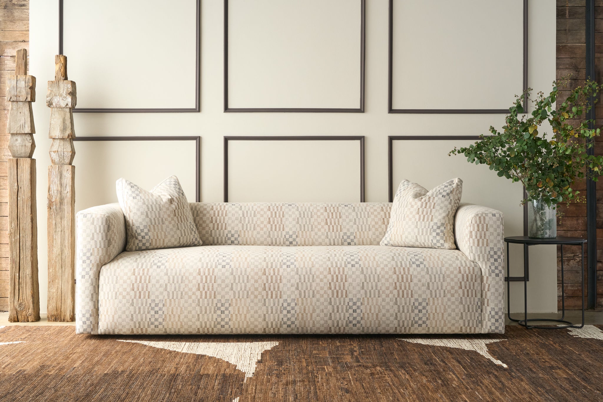  Patterned sofa in a room with wooden flooring and framed pictures on the wall. Photographed in Damas Mineral. 