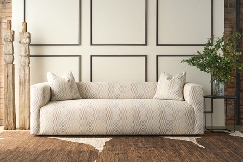 Patterned sofa in a room with wooden flooring and framed pictures on the wall. Photographed in Damas Mineral.